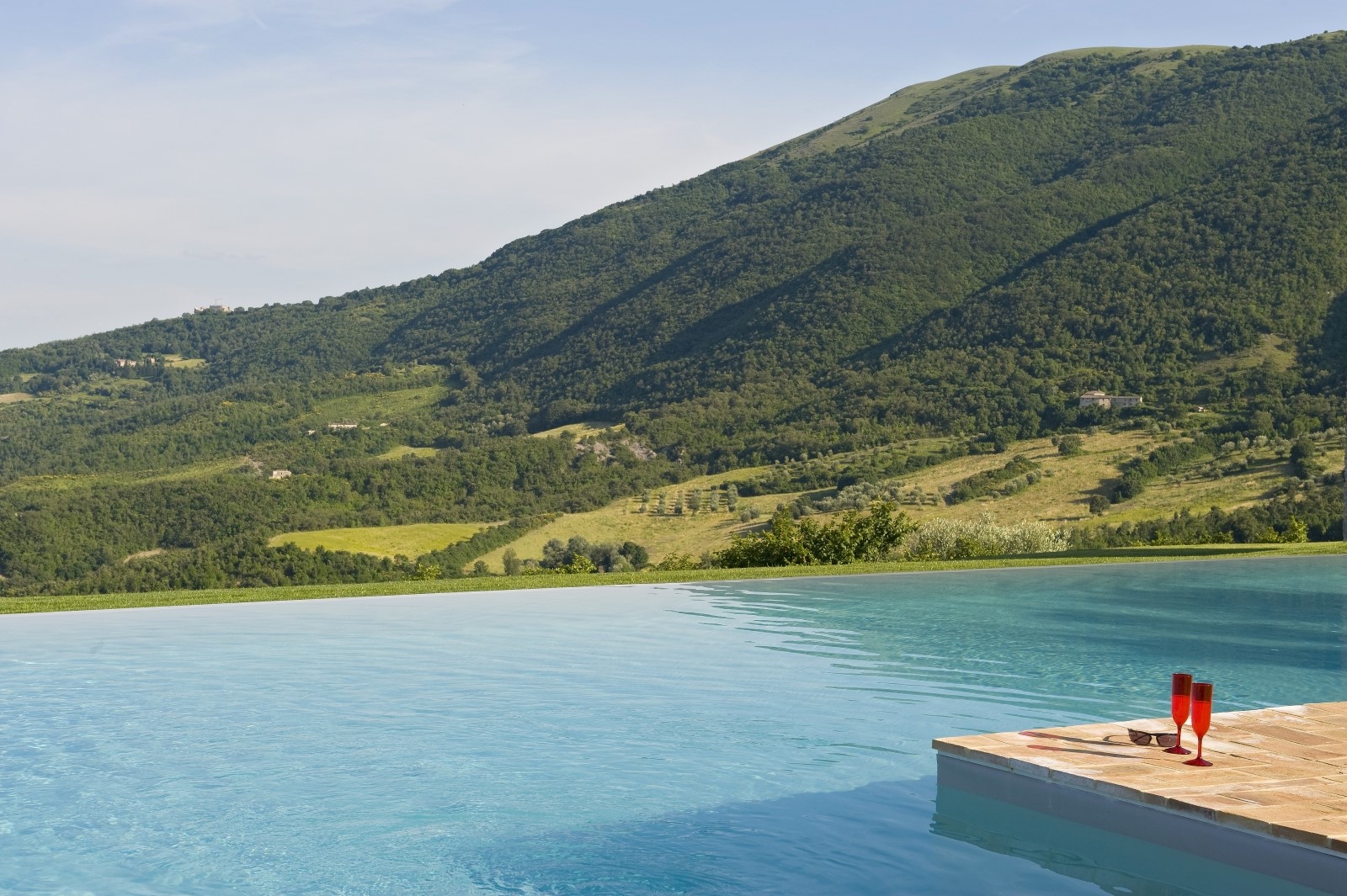 Infinity pool with glasses and view at Bel Canto in Umbria
