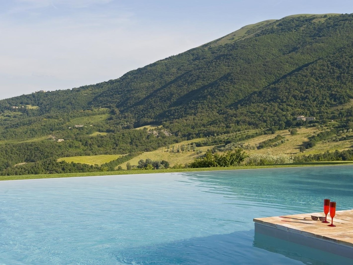 Infinity pool with glasses and view at Bel Canto in Umbria