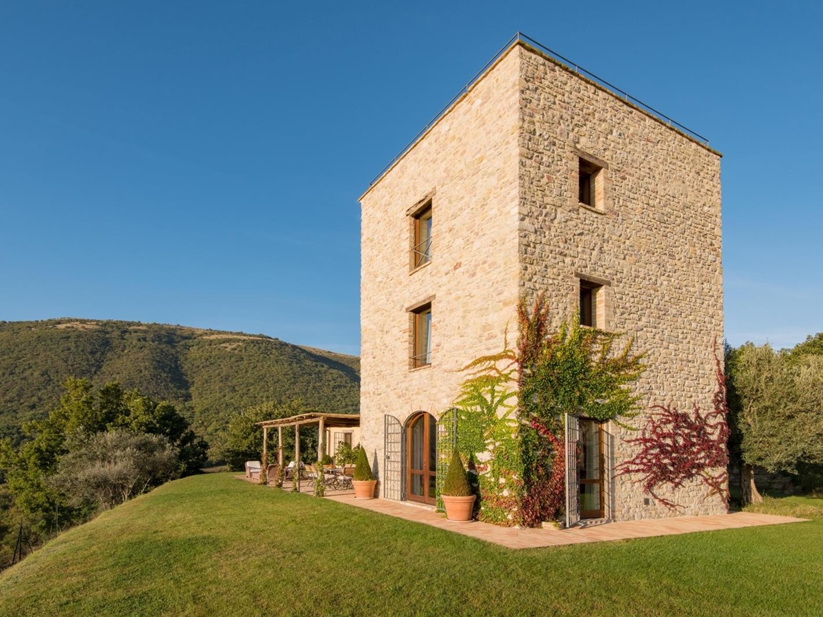 Garden and back of villa with patio, ivy, plants, trees and mountains at Bel Canto in Umbria, Italy