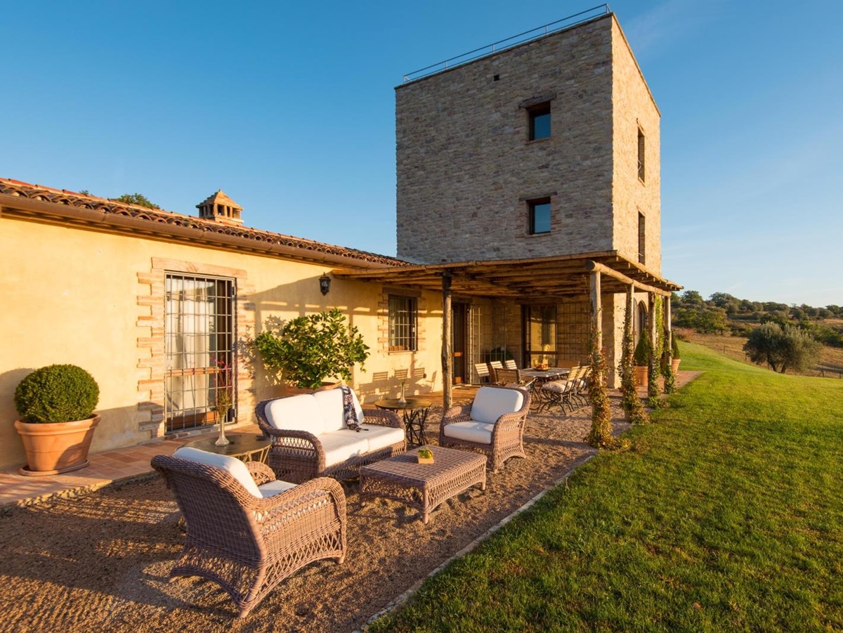 Patio with comfy chairs, coffee table, covered dining area, long table, plants and grass Bel Canto in Umbria, Italy