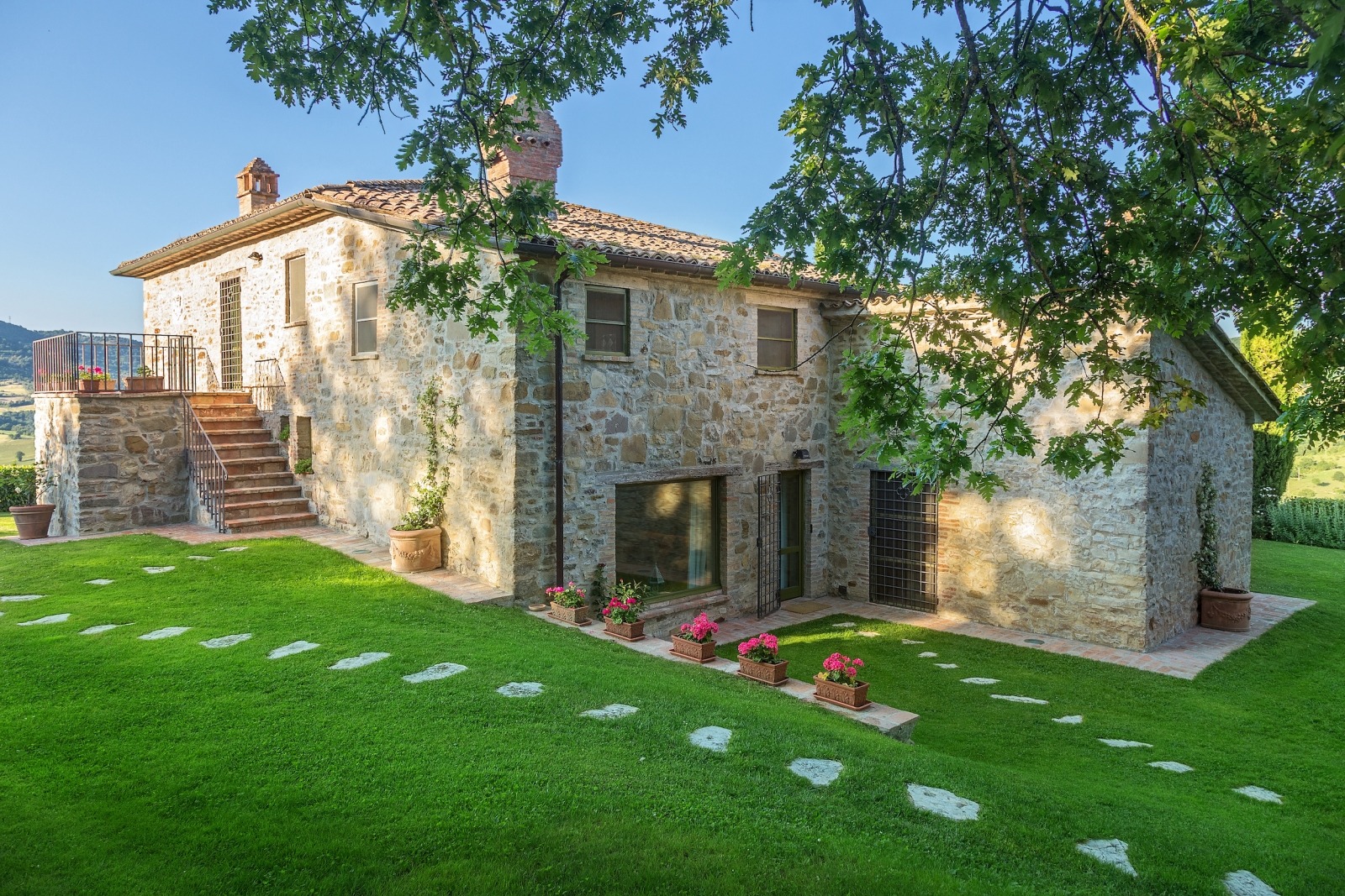 Exterior shot of villa and garden with flowers, plants and trees at Il Coccinella in Tuscany, Italy