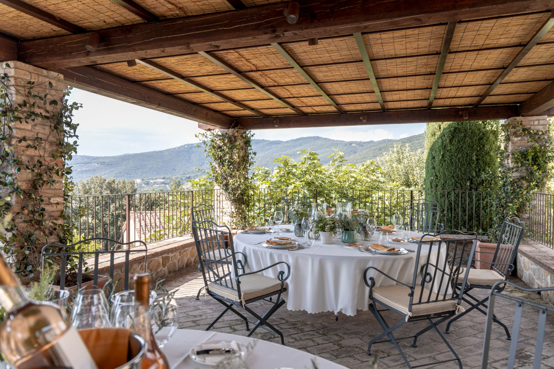 Outdoor dining area with circular tables overlooking the Umbrian views at Villa il Convento