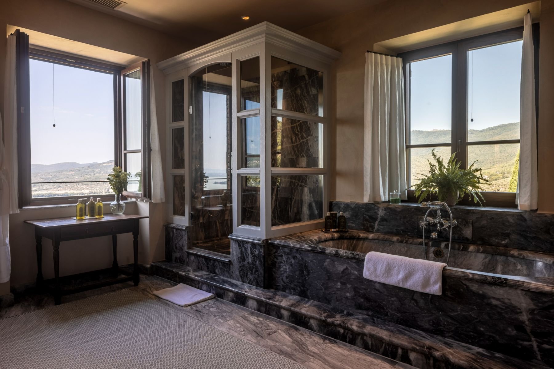 Bathroom with black marble bath and shower with large open window at Il Convento in Umbria