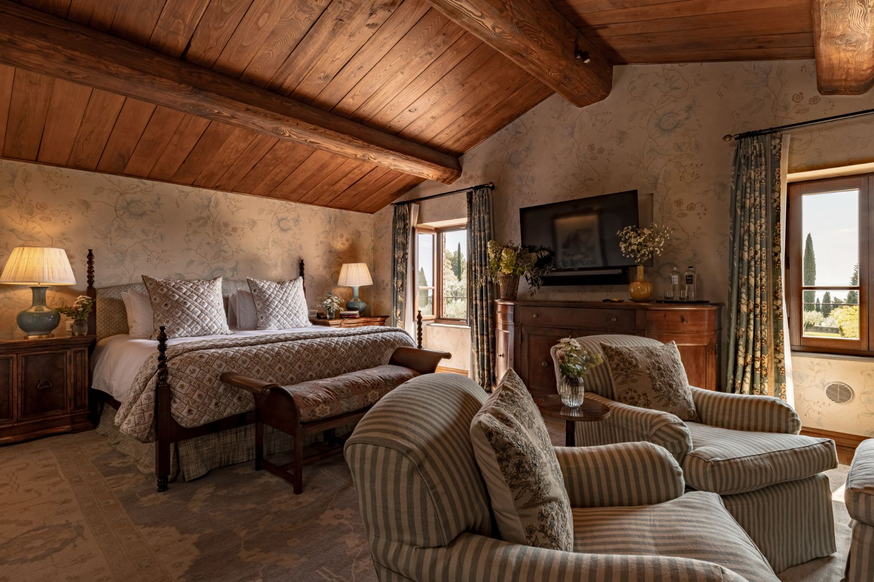Bedroom with large double bed and striped armchairs at Villa Il Convento in Umbria