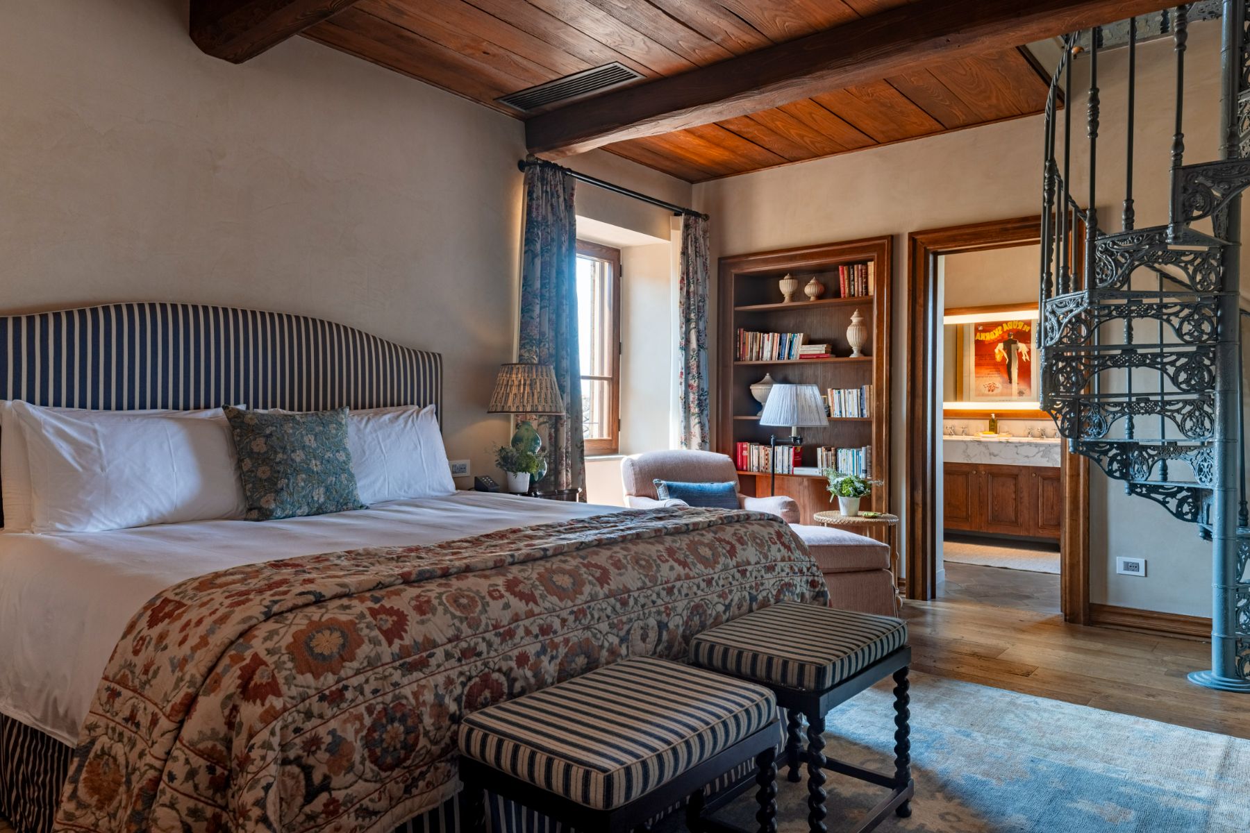 Large double bed with ensuite bathroom and stairs up to room at Villa Il Convento in Umbria