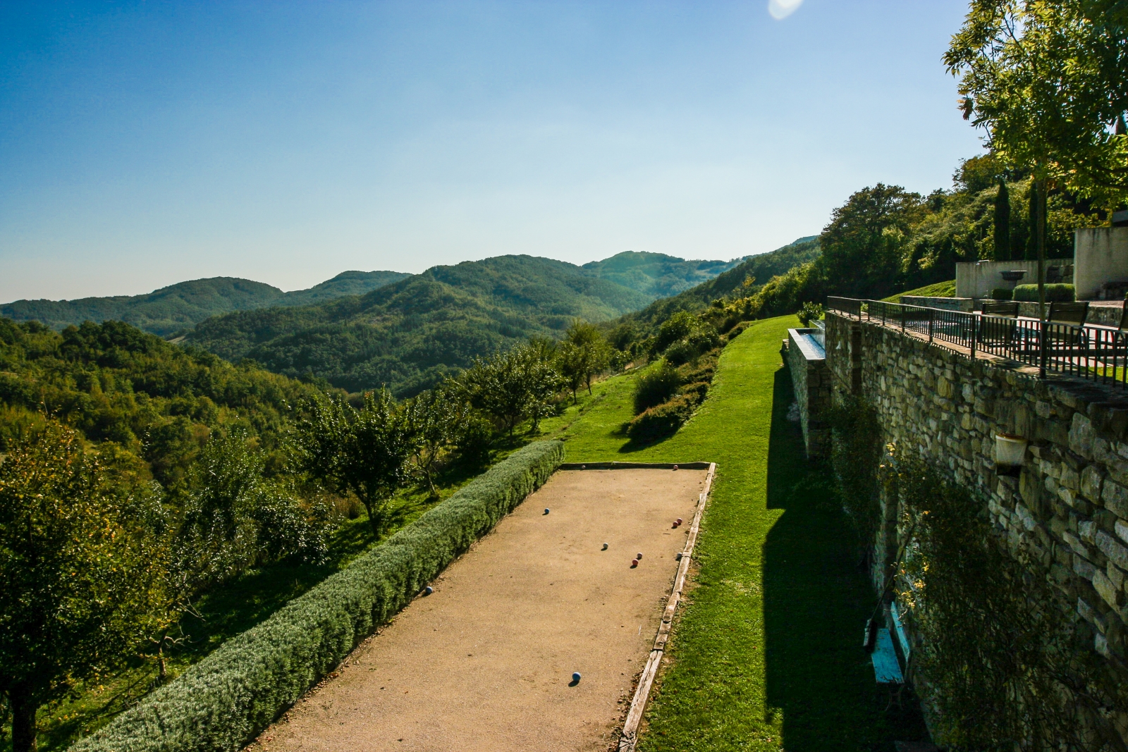 Bedroom with double bed, bedside tables, lamps, radio, windows and ceiling beams at La Spiga in Umbria, Italy