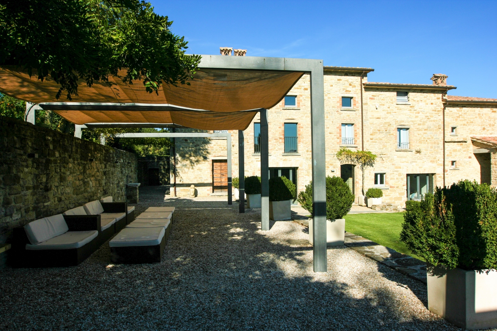 Covered seating area in garden with sofas and plants at La Spiga in Umbria, Italy
