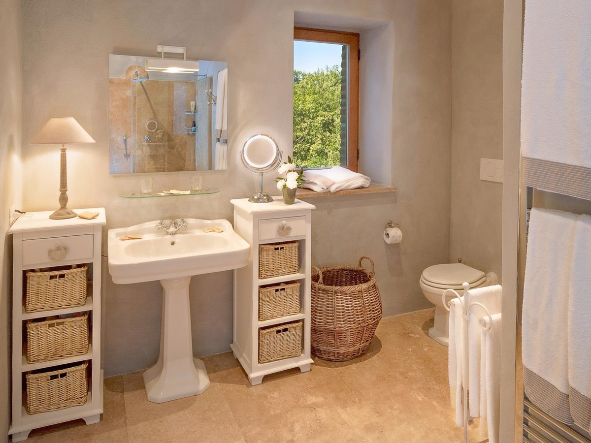 Bathroom with sink, mirrors, shelves, lamp, toilet and towel rail at Monticello in Umbria, Italy
