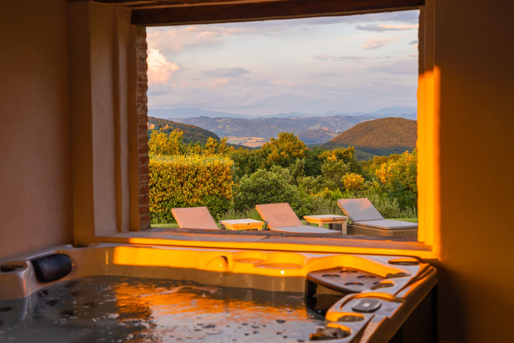 Jacuzzi at Villa Arpeggio in Umbria next to an open window with view of sun loungers and rolling hills