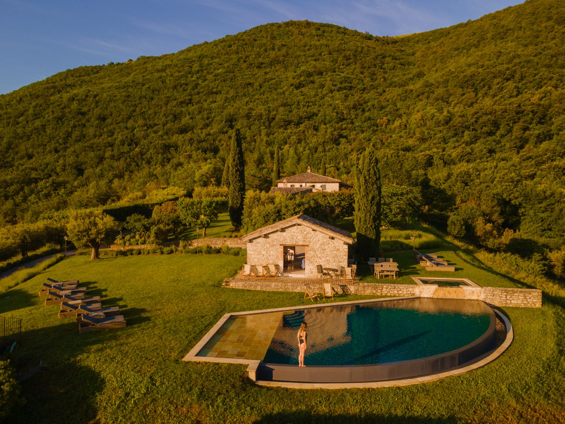 View of the outdoor pool with Villa Arpeggio in the background and Umbrian hills