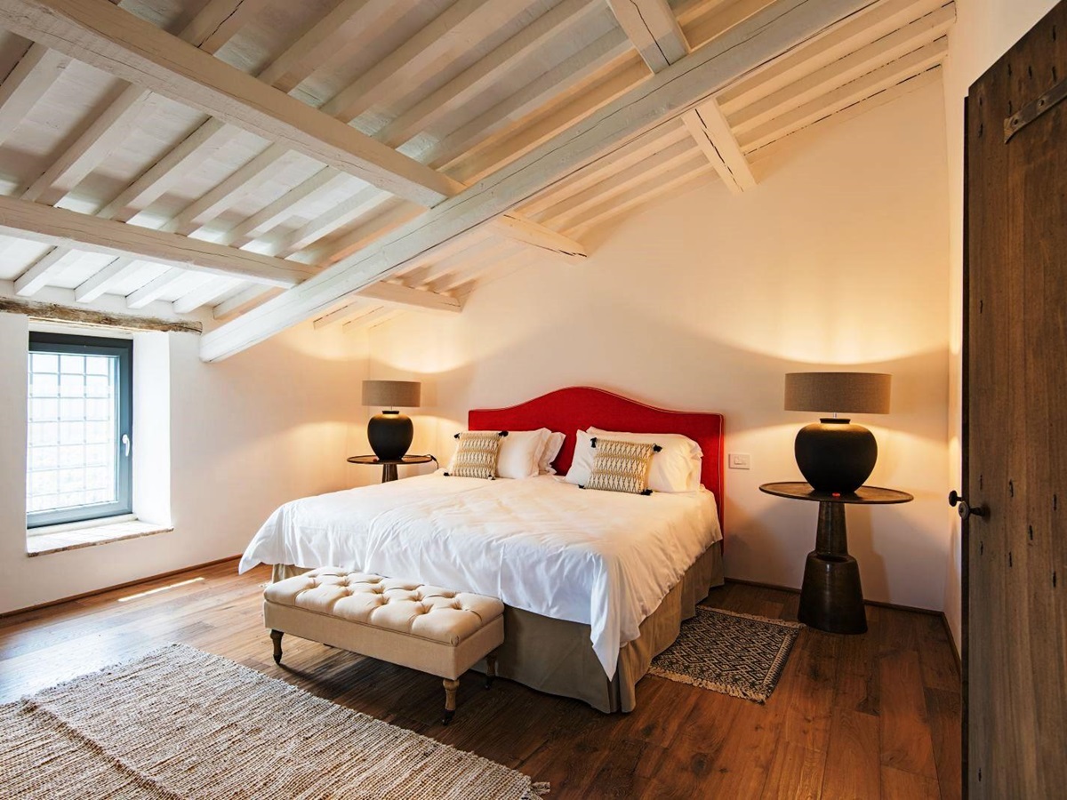 Bedroom with double bed on wooden floor with slanted white beamed ceiling at villa del conte in umbria, Italy
