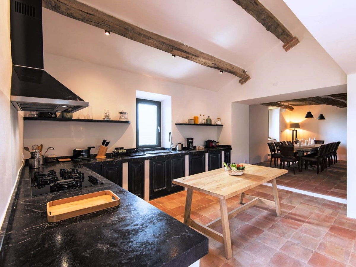 kitchen with tiled floor and units with black marble tops leading through to dining area at villa del conte in umbria, Italy