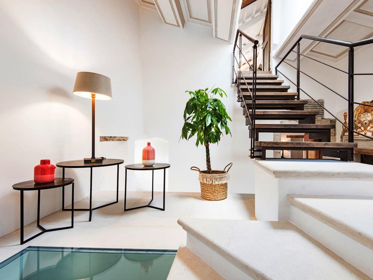 hallway with 3 small tables with lamp and vases next to wooden stairs at villa del conte in umbria, Italy