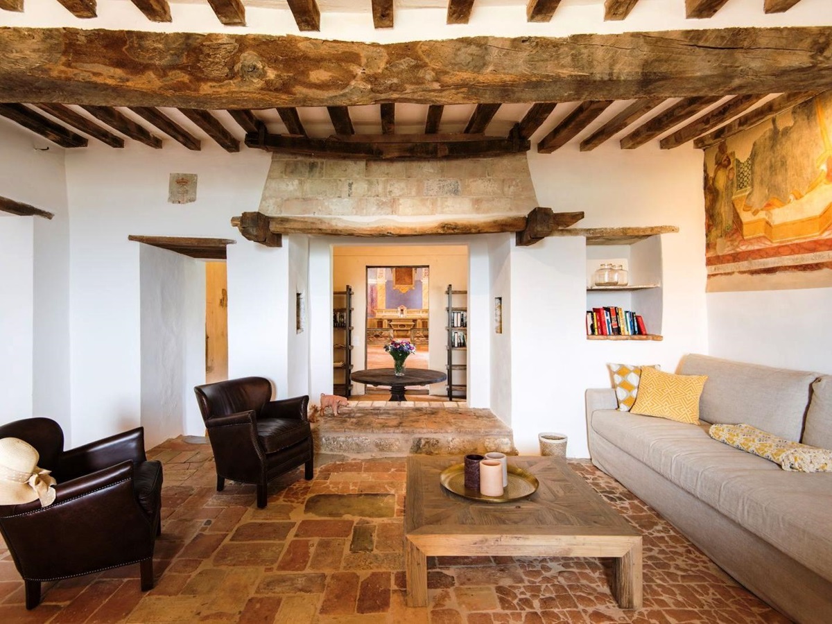 sitting room with sofa, 2 brown chairs and wooden coffee table on brick foor at villa del conte in umbria, Italy