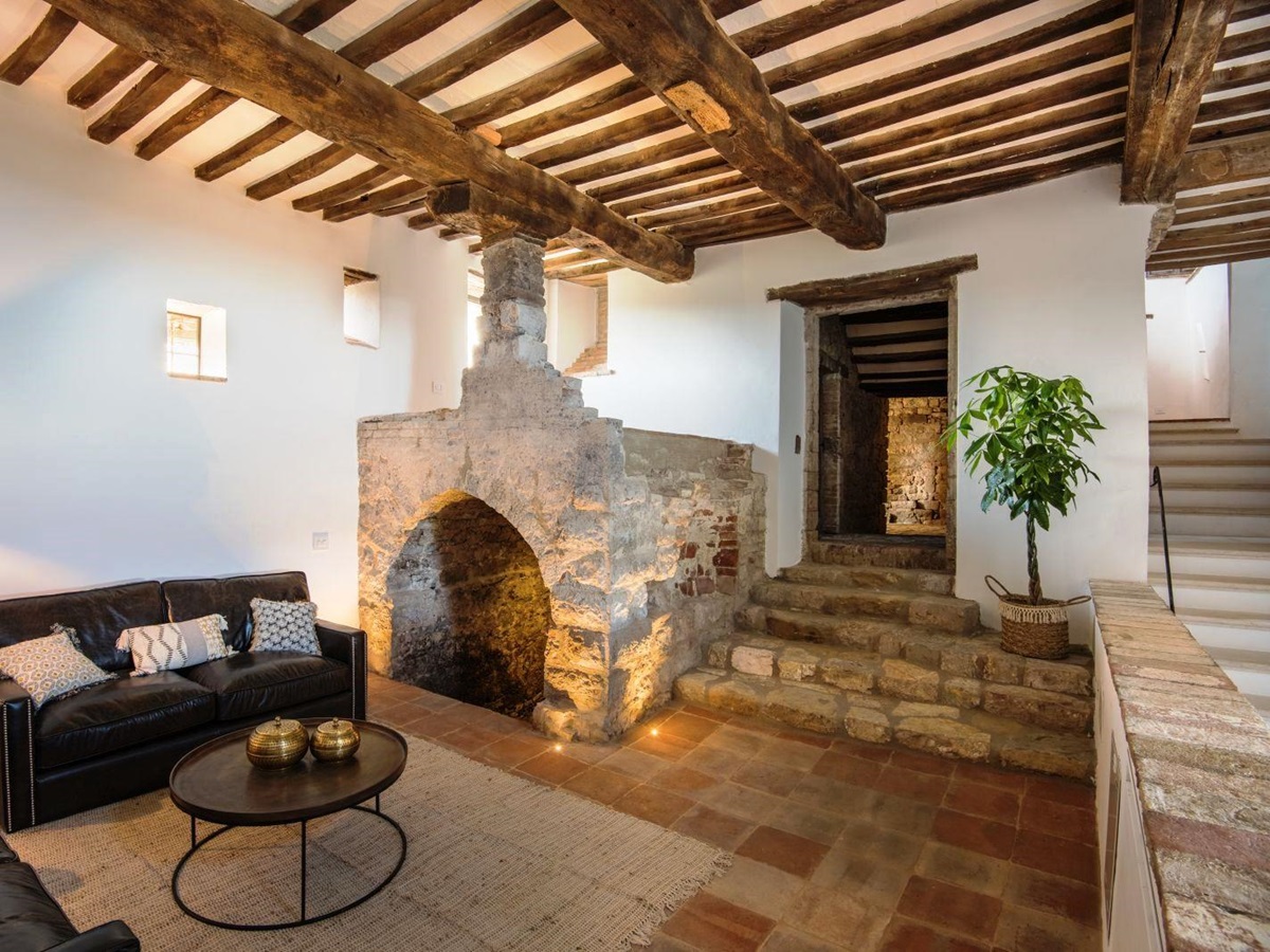 stone steps leading down to cosy sitting room with 2 brown leather sofas and round table at villa del conte in umbria, Italy