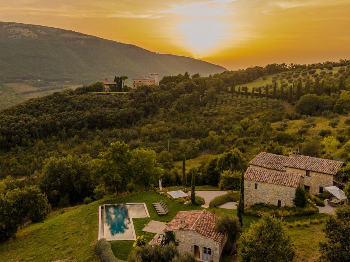 Drone view of Villa Piuma in Umbria with the sun setting featuring the outdoor pool and rolling hills