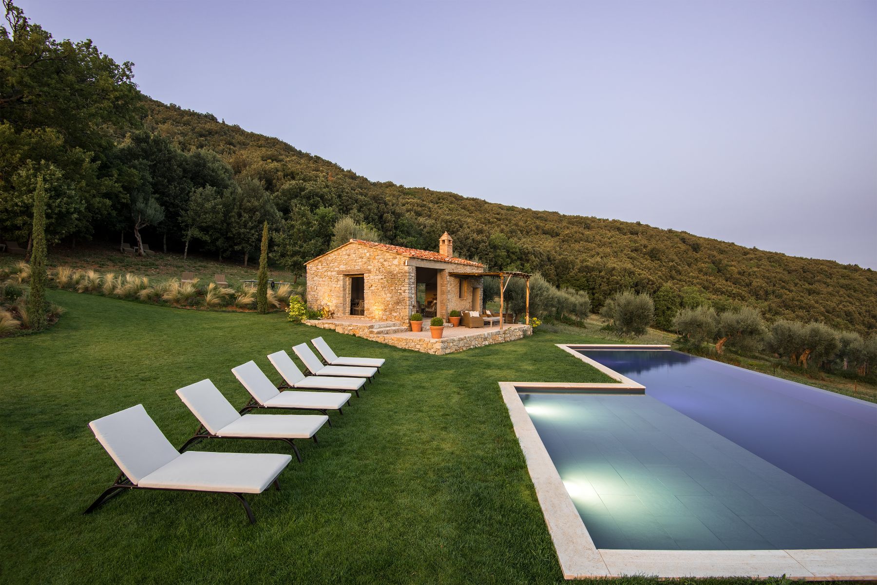 View of the outdoor pool and white sun loungers at Villa Piuma in Umbria