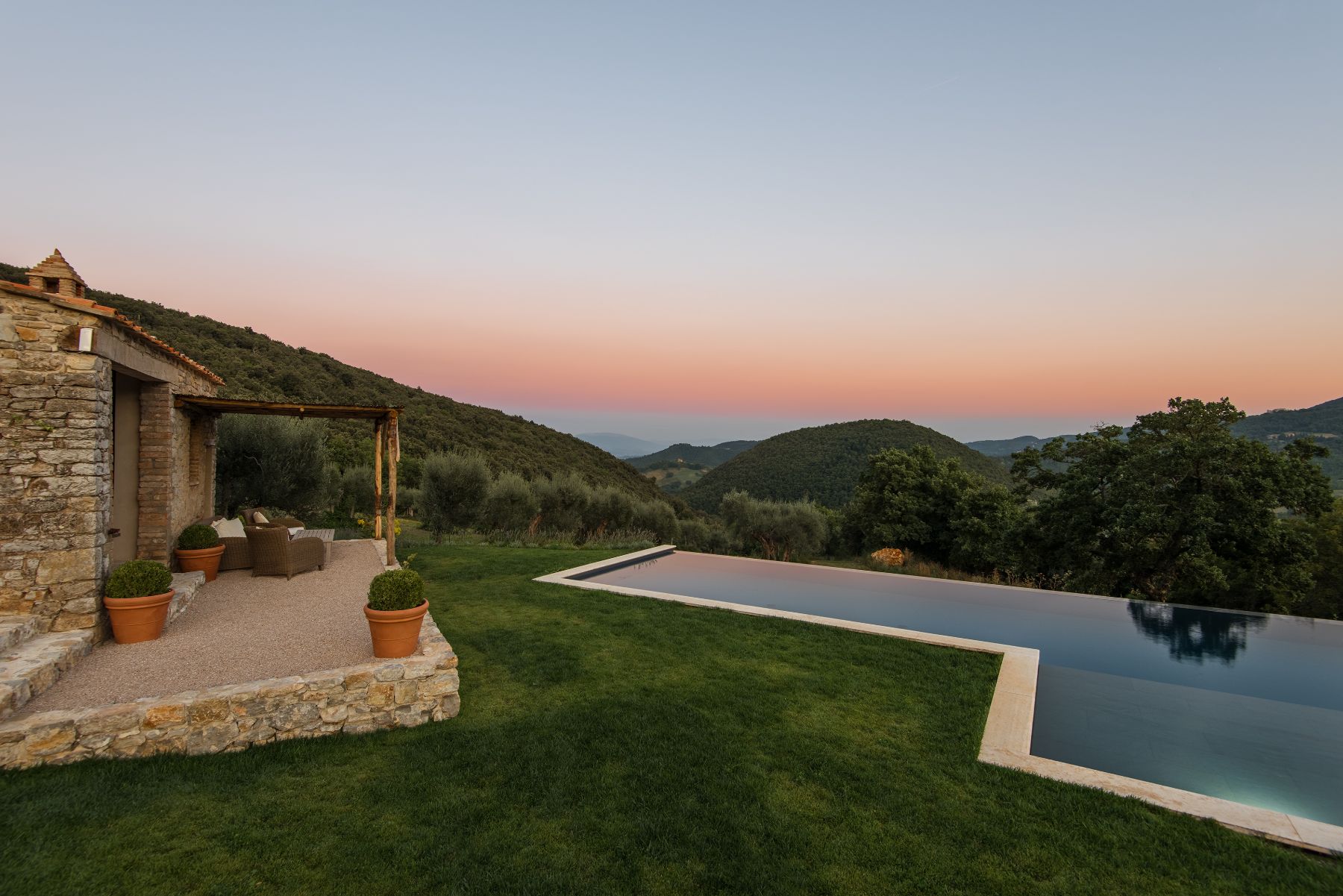 Pool with sunset in the background and rolling hills at Villa Piuma in Umbria