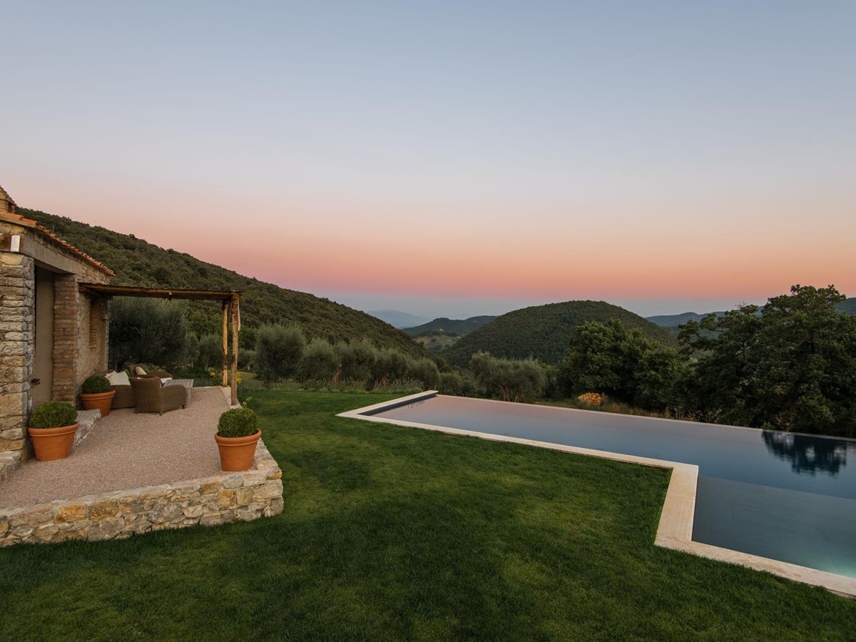 Pool with sunset in the background and rolling hills at Villa Piuma in Umbria