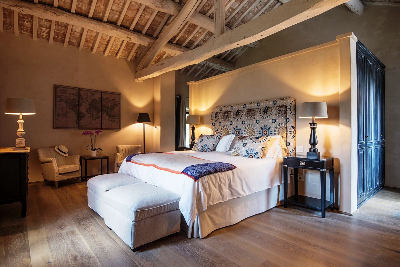 Double bedroom with closets with blue doors, two comfy chairs and tables at at Villa Piuma in Umbria, Italy