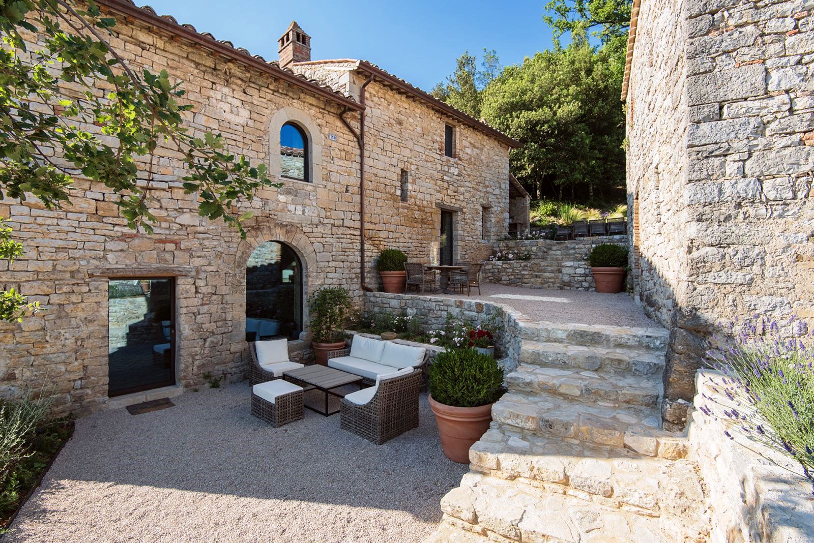 Panoramic terrace with sofas and chairs in the piazzetta between house and annex at Villa Piuma in Umbria, Italy