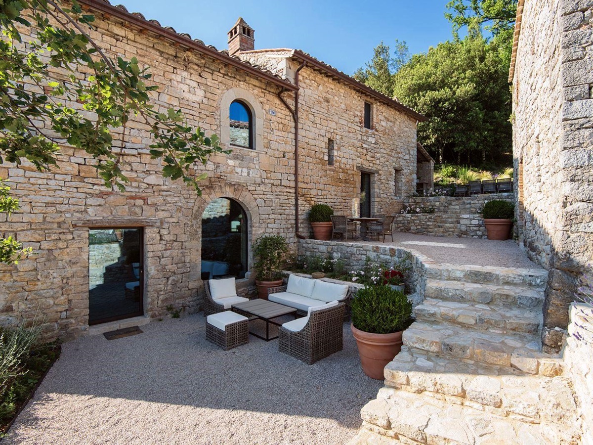 Panoramic terrace with sofas and chairs in the piazzetta between house and annex at Villa Piuma in Umbria, Italy