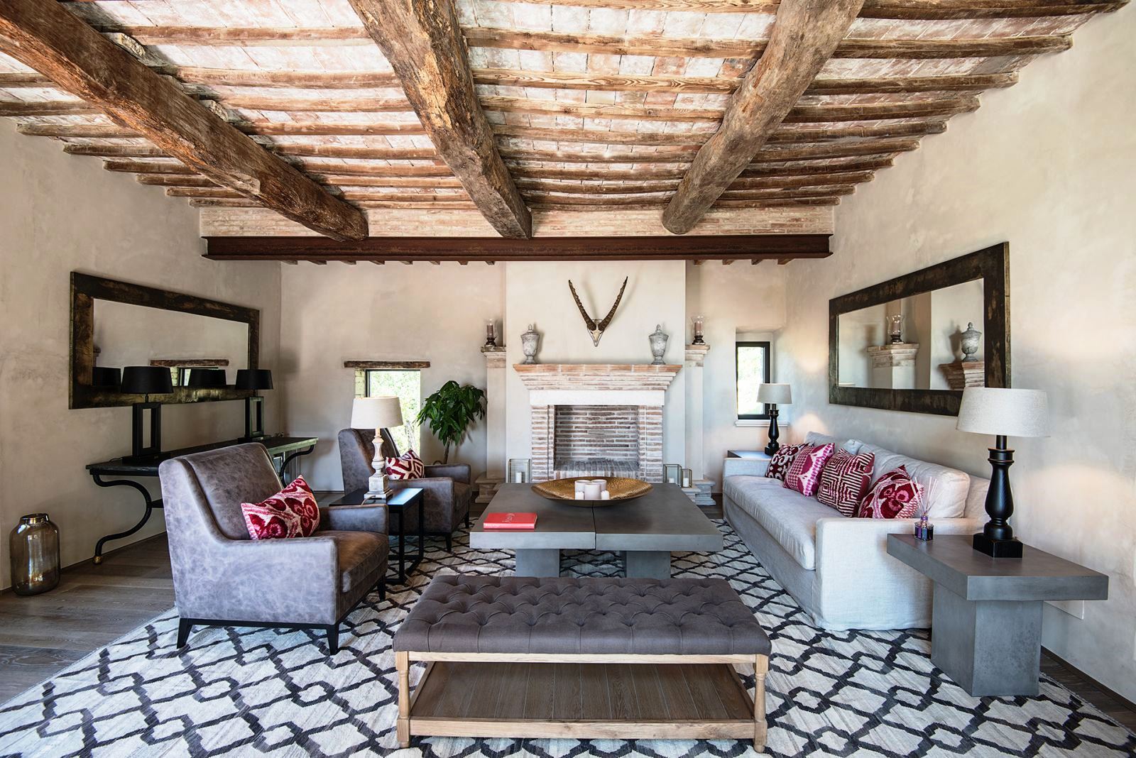Sitting room with patterned floor, beamed ceiling, sofa, chairs and marble tables at Villa Piuma in Umbria, Italy
