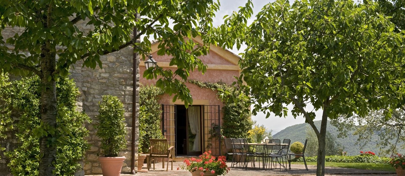 Front of small chapel with orchard trees in the foreground at Villa Pizzicato in Umbria