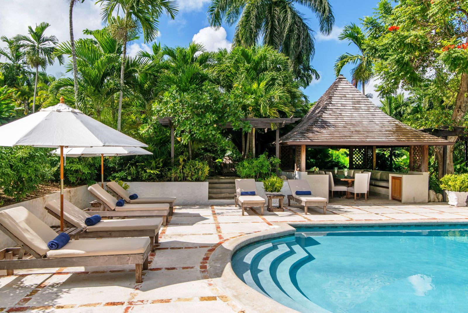 edge of swimming pool with sun loungers and umberellas at Almond Hill Villa, Montego Bay Jamaica
