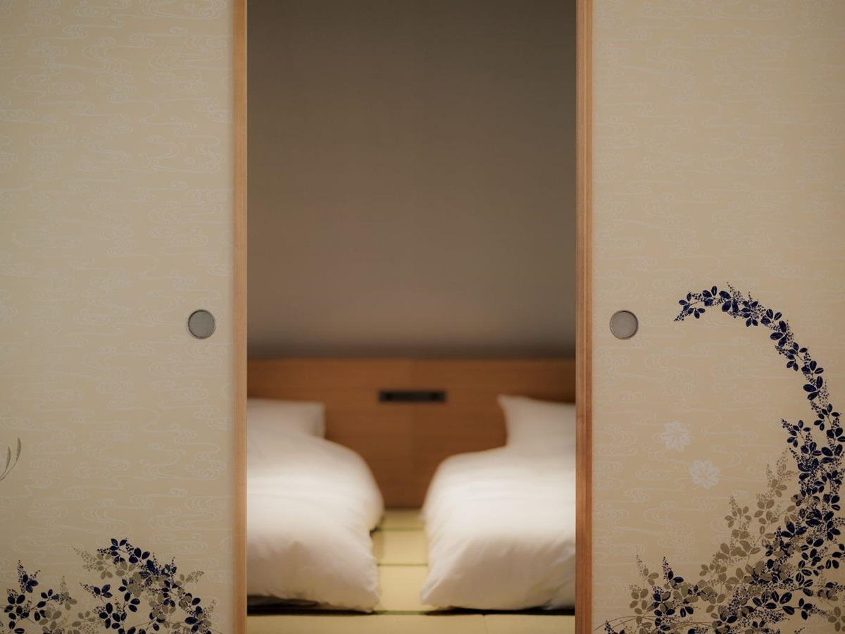 Beds viewed through the mirror in a guest suite at Naoshima Ryokan Roka in Japan