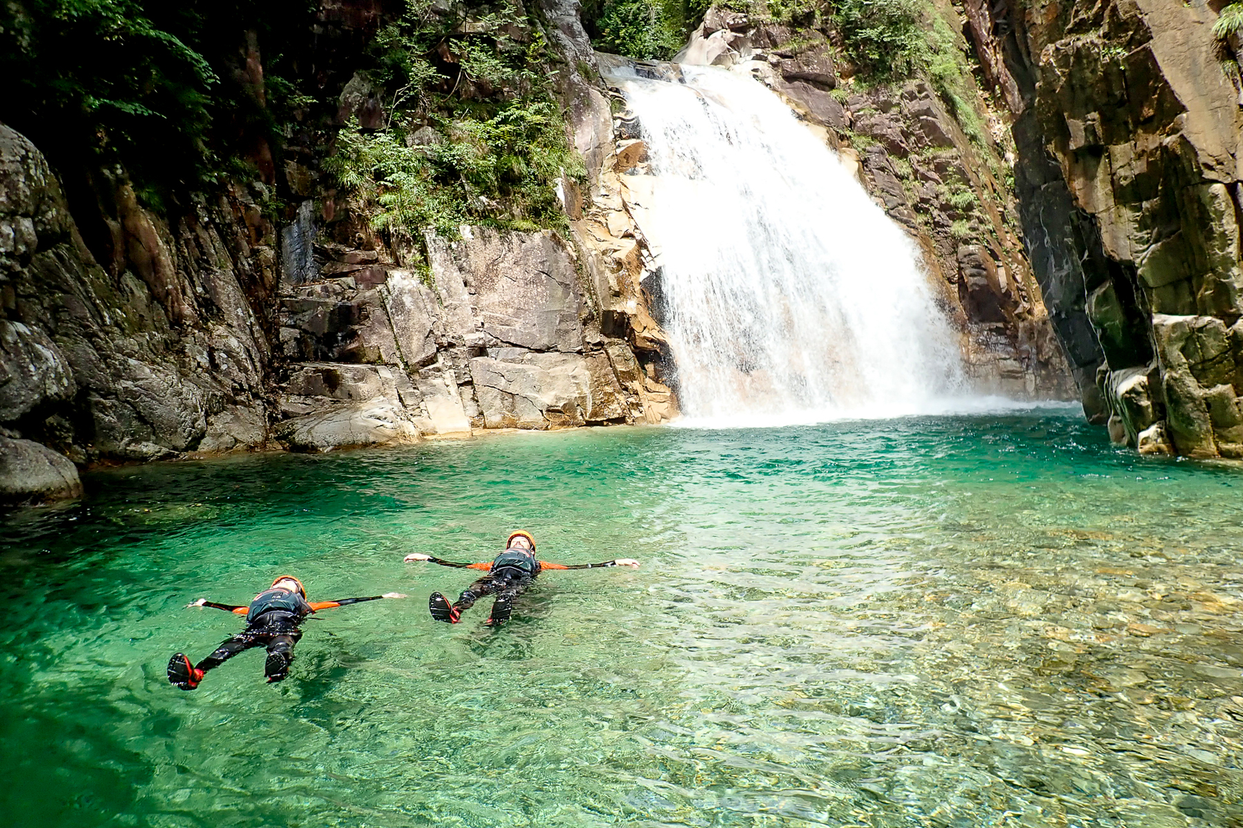 Guests floating around the waterfall at Zenagi