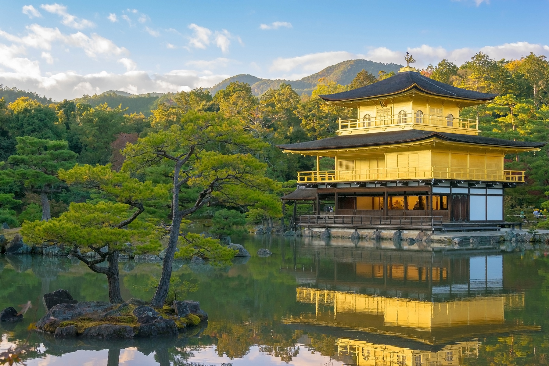 The reflection of Knkakuji Temple, the Golden Pavillion, on the lake in front with woodland all around