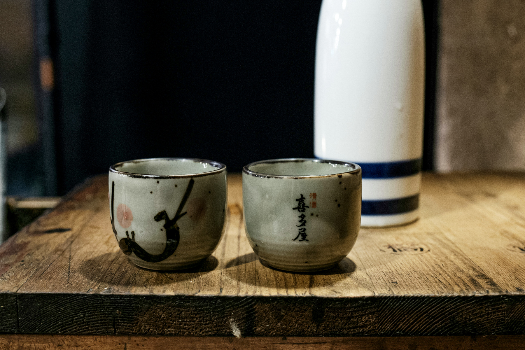 Close up of two sake cups in front of a sake bottle