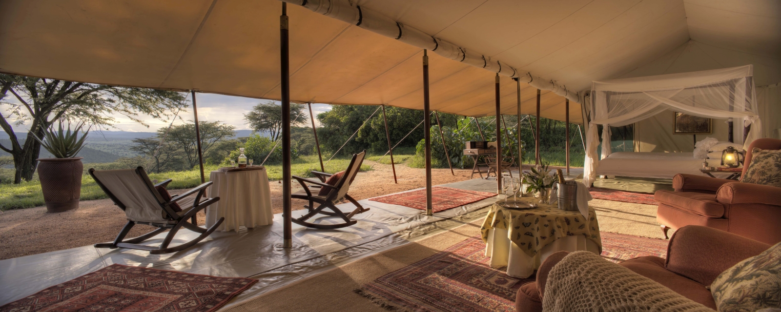 Honeymoon tent with four-poster bed, seating area and private terrace at luxury safari lodge Cottar's 1920's Safari Camp in the Maasai Mara, Kenya