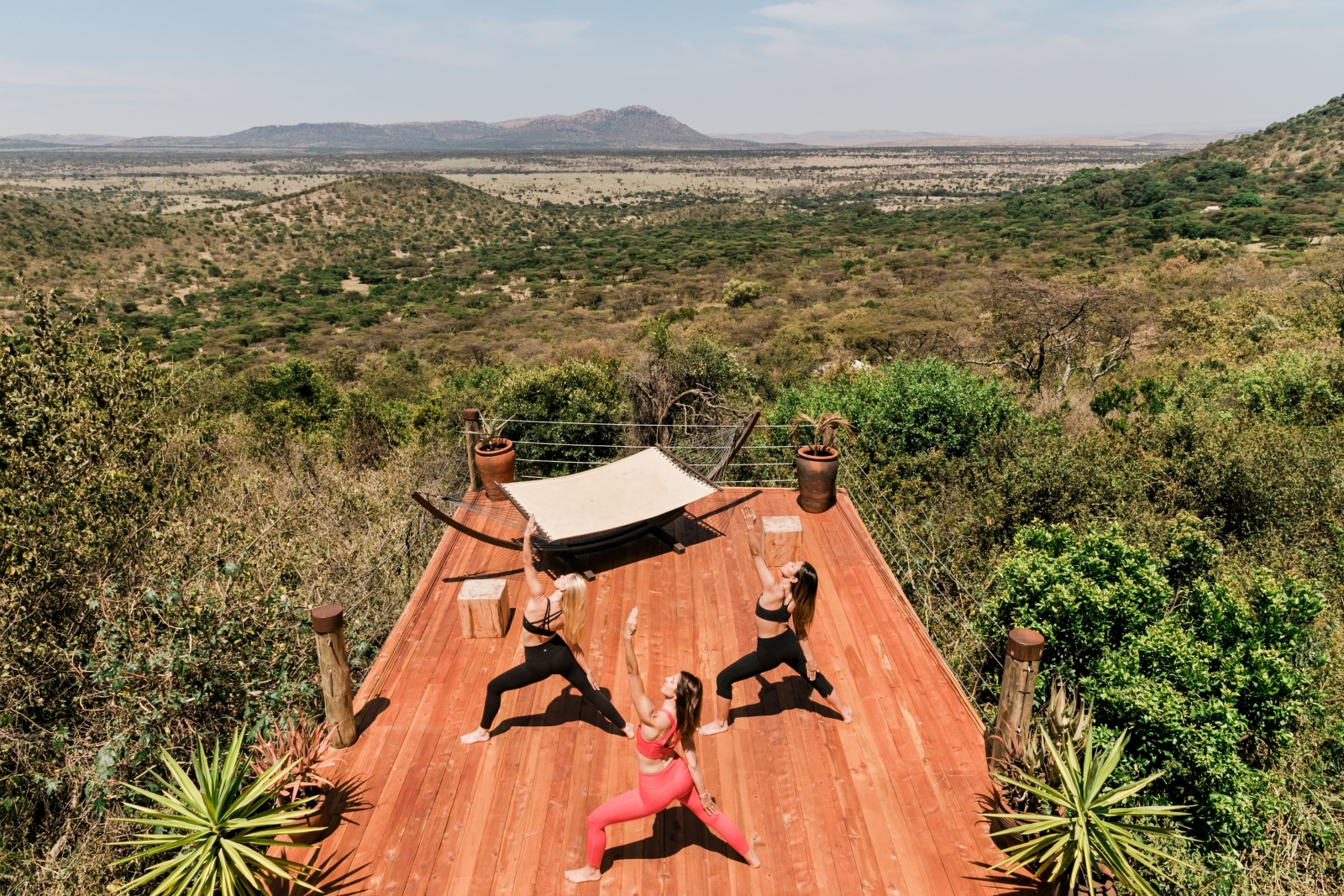three women practicing yoga on the deck of Cottar's Bush Villa