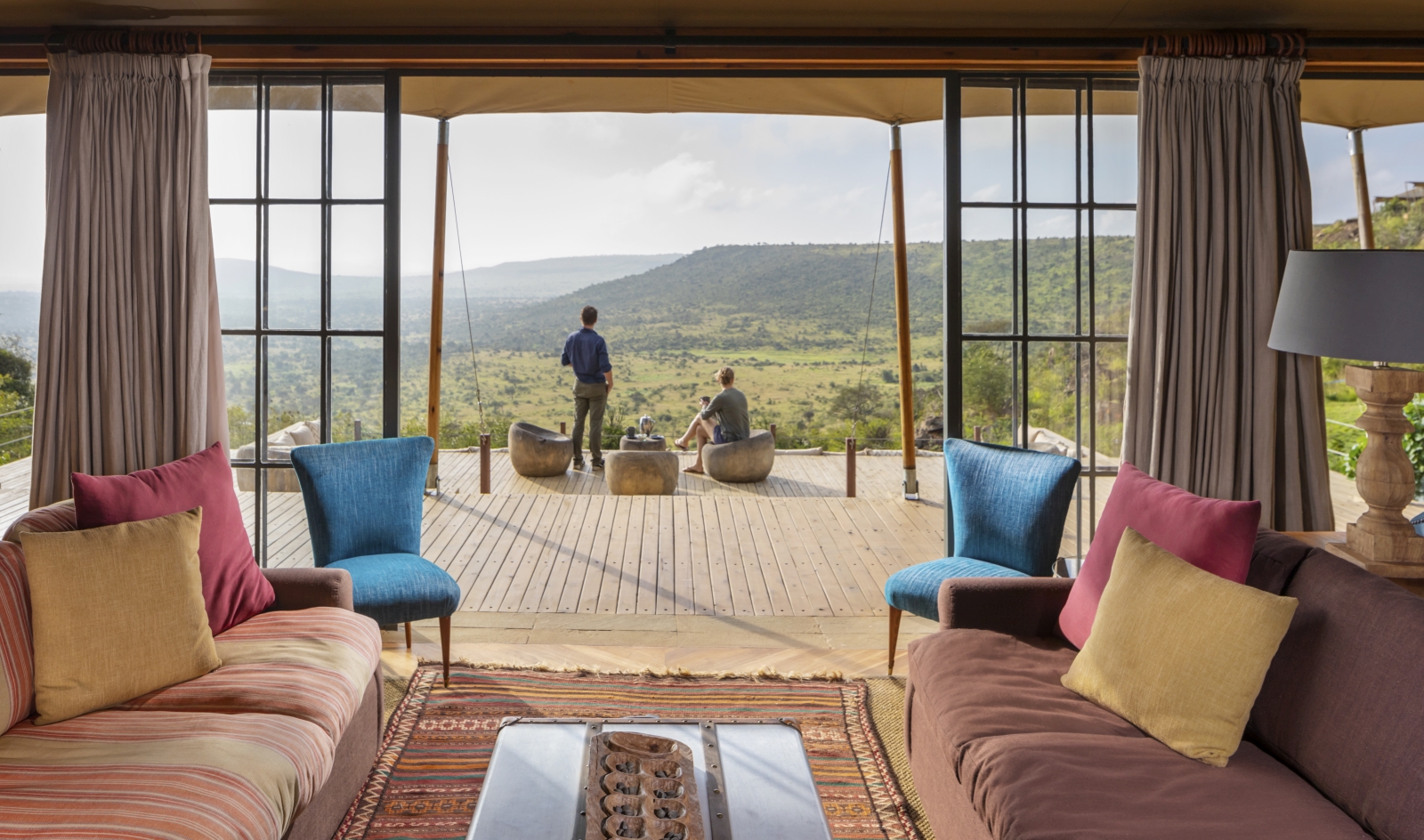 two guests enjoying the view from the main deck outside the lounge at luxury safari lodge Lodo Springs in the Laikipia region of Kenya