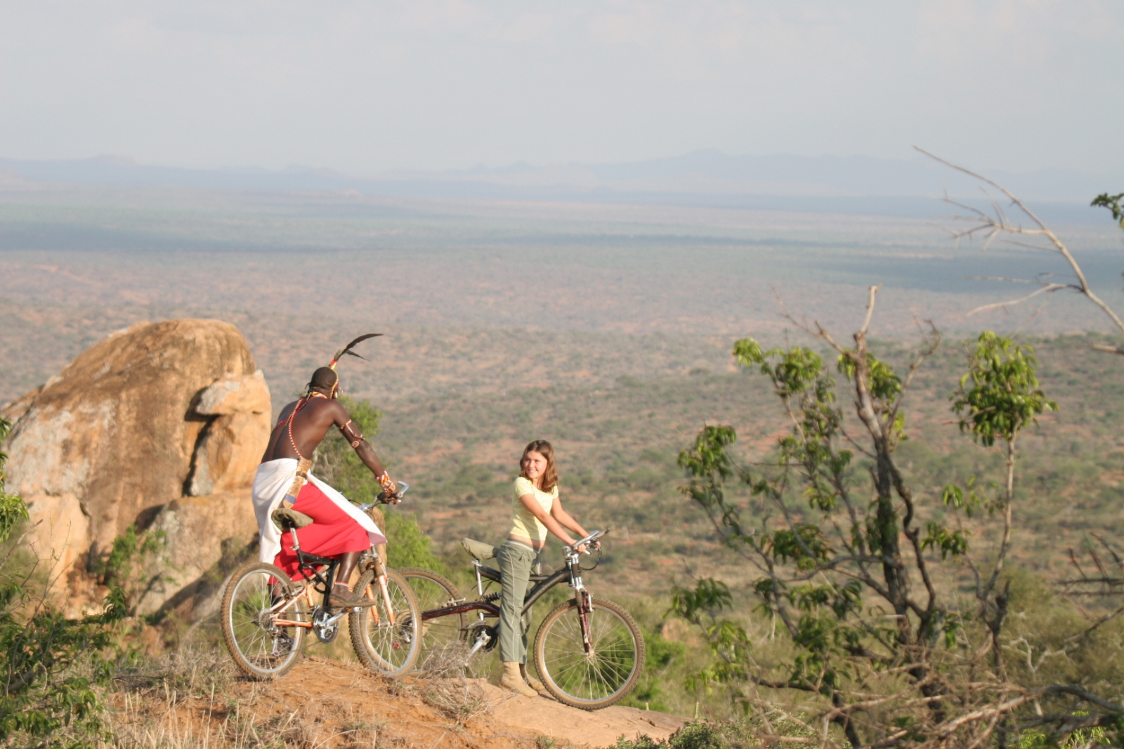 a guests and Masai guide mountain biking through the African bush at luxury safari lodge Lodo Springs in the Laikipia region of Kenya