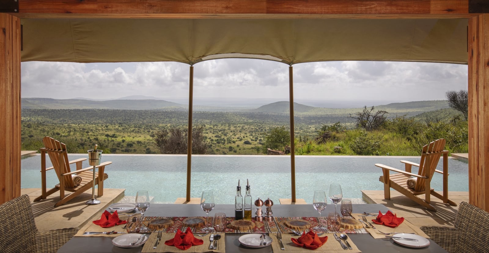 Table set for dinner overlooking the pool and the vast African bushveld at luxury safari lodge Lodo Springs in the Laikipia region of Kenya