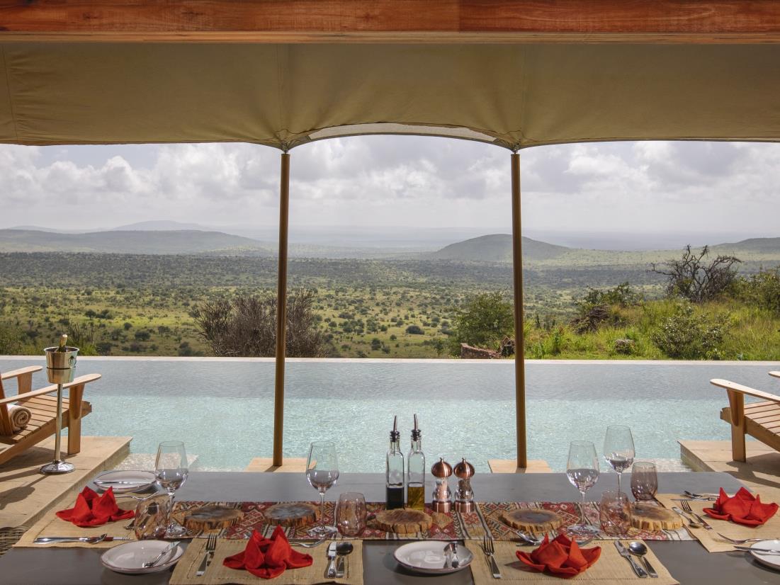 Table set for dinner overlooking the pool and the vast African bushveld at luxury safari lodge Lodo Springs in the Laikipia region of Kenya