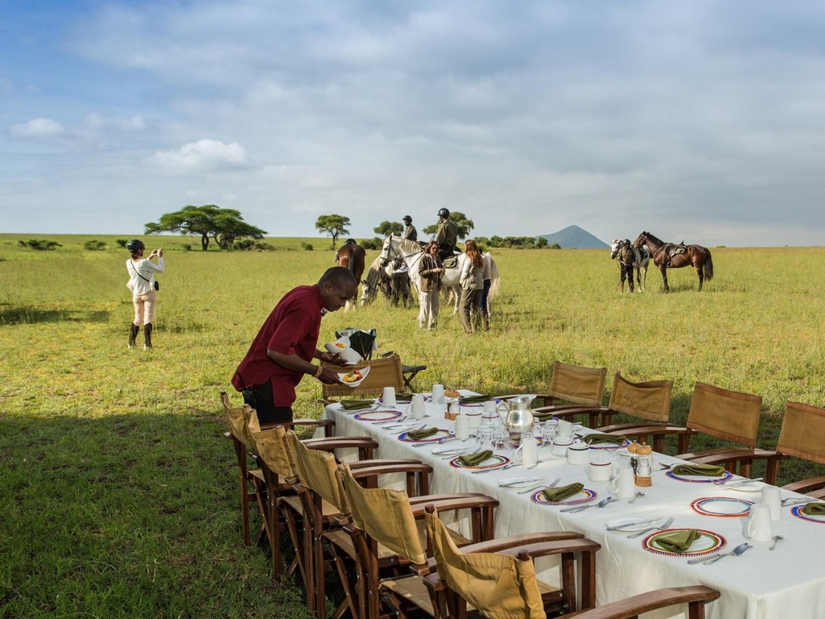 Guests arriving at a bush breakfast after a morning ride during a stay at luxury lodge Ol Donyo in Kenya