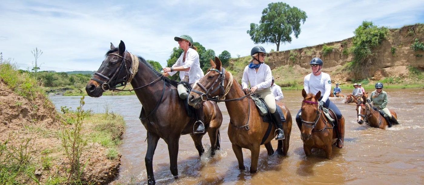 Horses and riders crossing river on Kenya riding safari