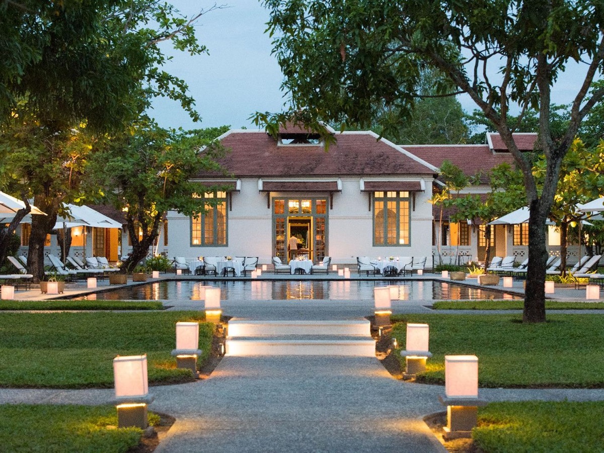 The pool and grounds at Amantaka Laos lantern lit at dusk