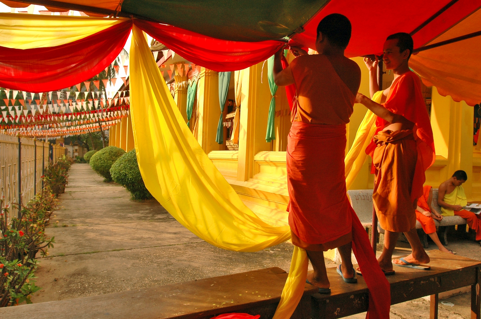 Two monks putting up bright yellow and orange fabric