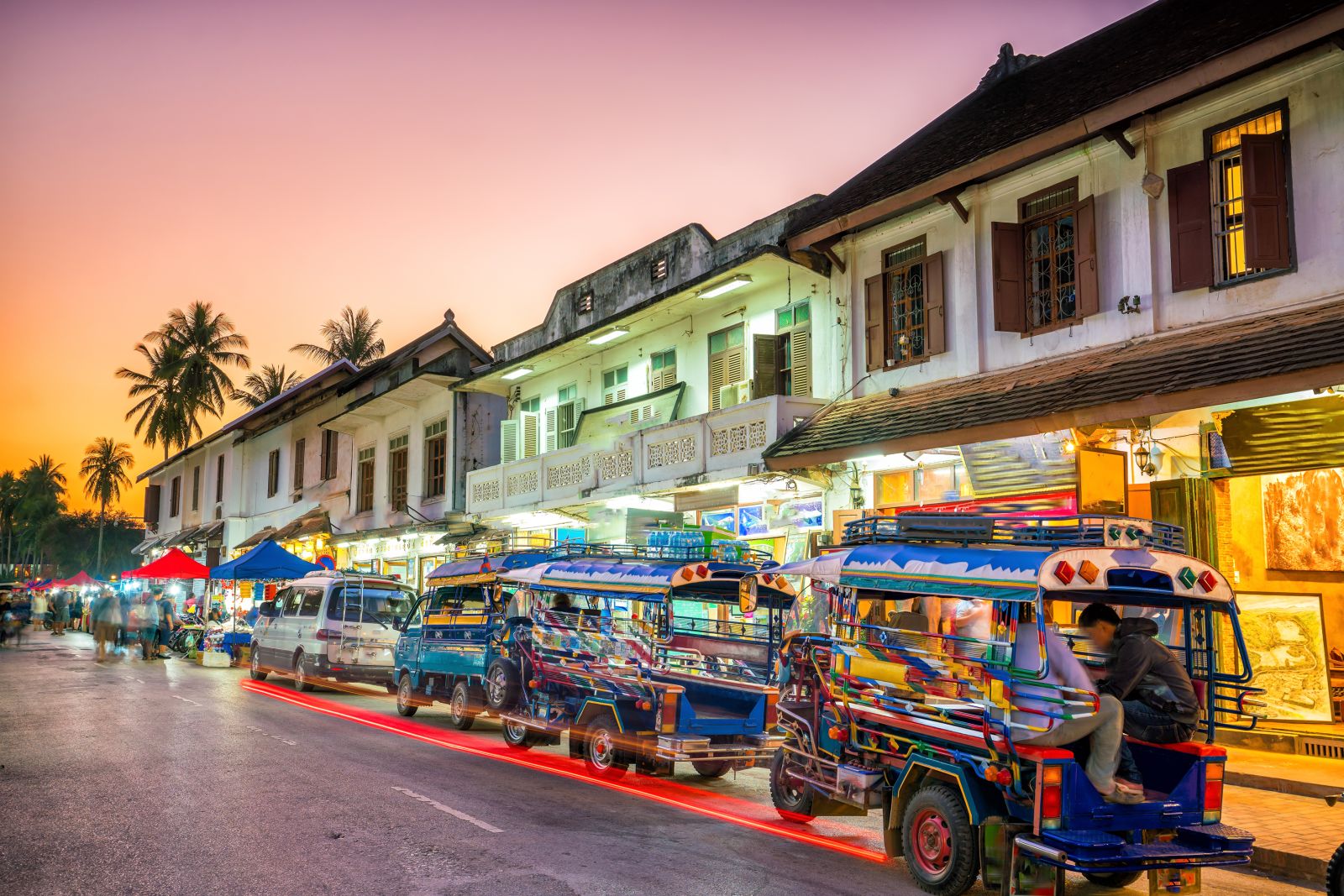 Tuk-tuks and vibrant neon lights in Luang Prabang at sunset Laos