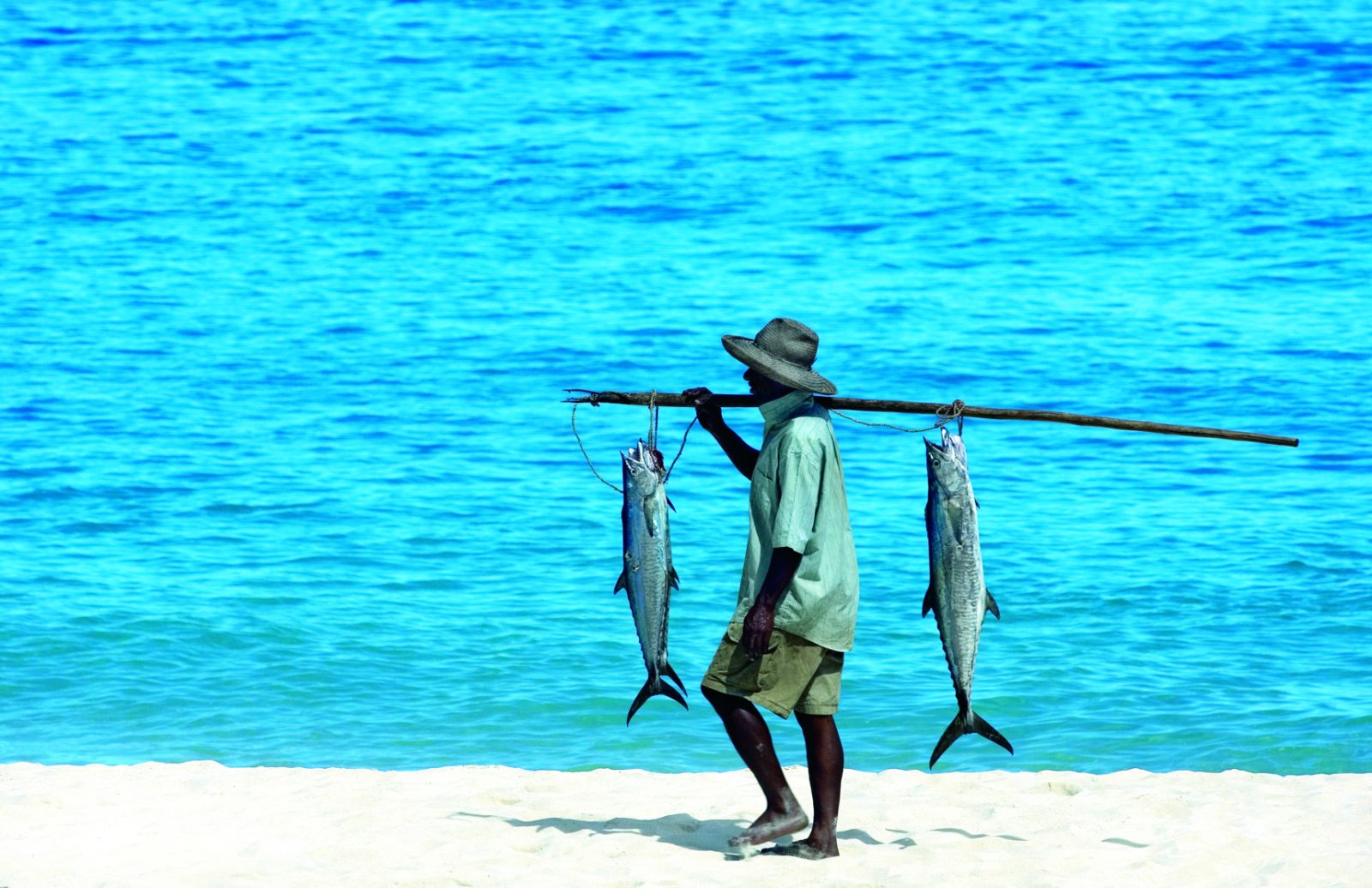 Fisherman carrying two large fish near the Constance Tsarabanjina in Madagascar