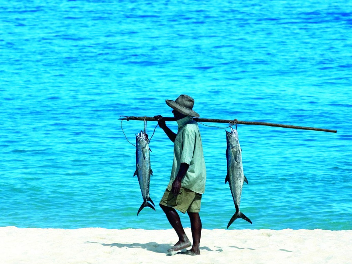 Fisherman carrying two large fish near the Constance Tsarabanjina in Madagascar