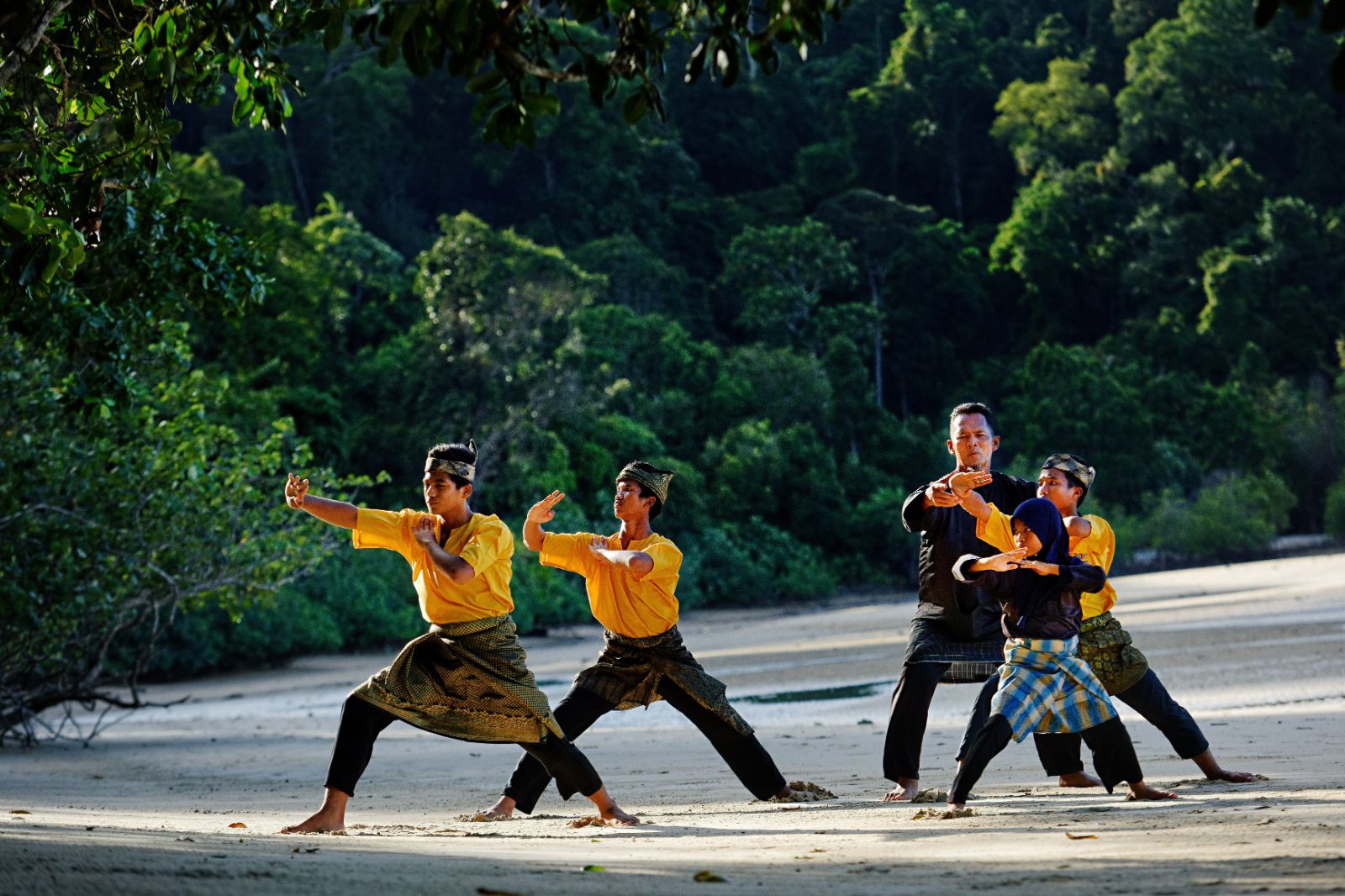 A group performing Silat on the beach at luxury resort The Datai