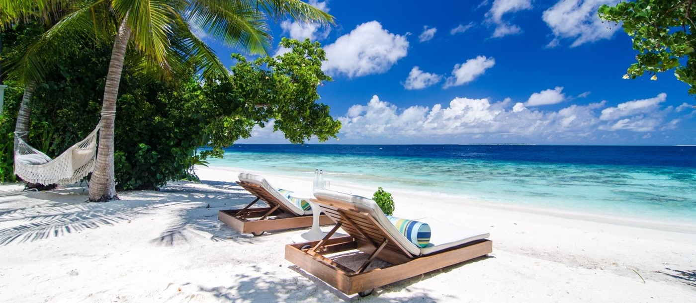 Two sunloungers on the white sand beach of luxury resort Amilla in the Maldives