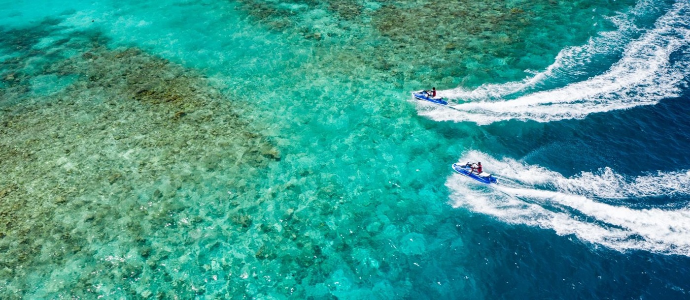 Two guests jetskiing in the Indian Ocean at luxury resort Amilla in the Maldives