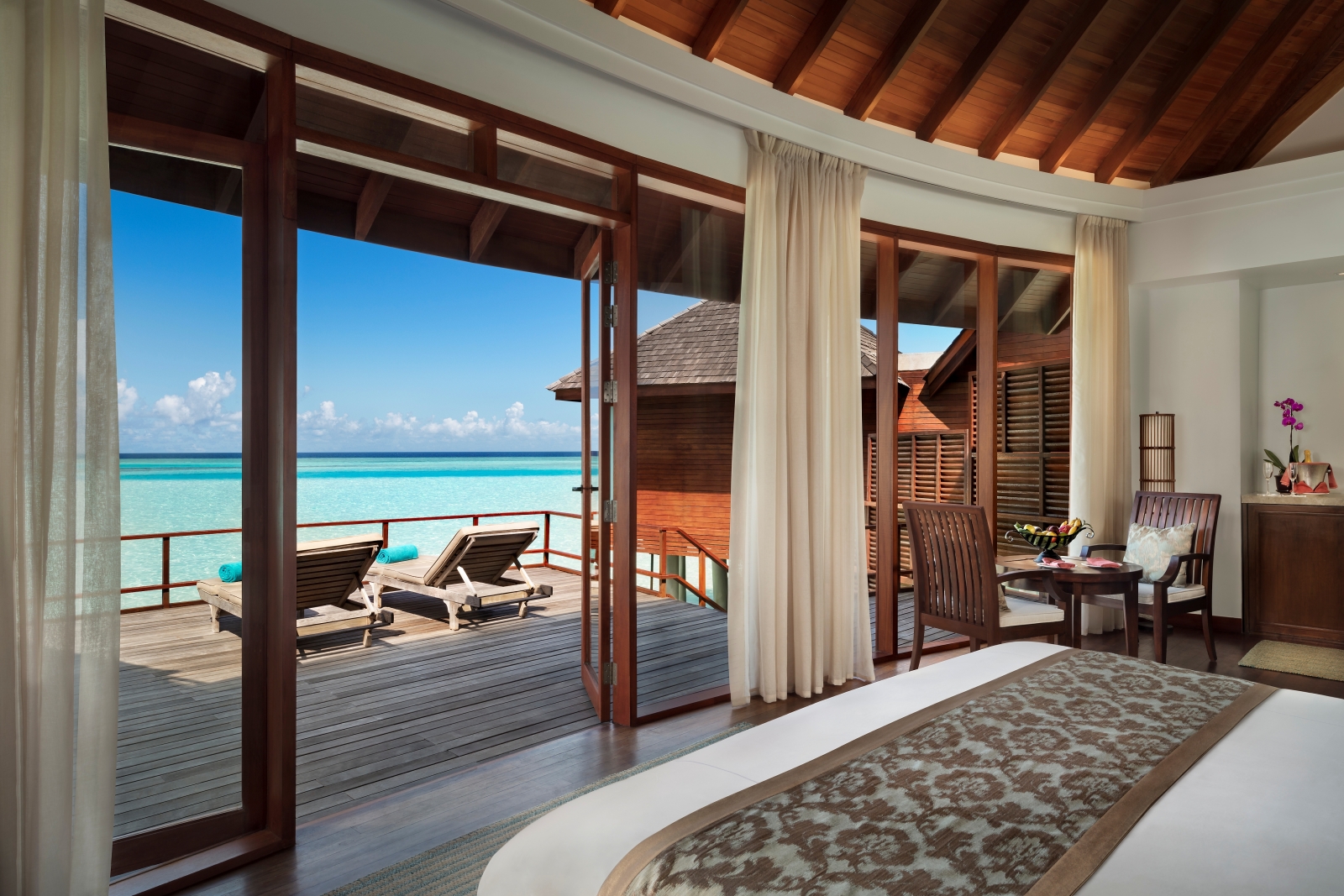 Bedroom and private deck of an over water villa at luxury resort Anantara Dhigu in the Maldives